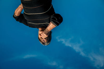 Low section of woman standing against blue sky