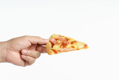 Close-up of hand holding pizza over white background