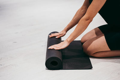 Midsection of woman rolling mat at gym