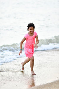 Full length of girl running on shore at beach