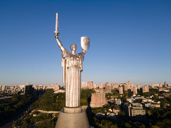 Statue in city against clear blue sky