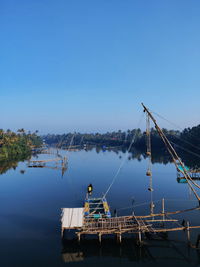Fishing boat in river against clear blue sky
