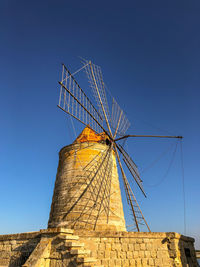 Low angle view of windmill against clear blue sky