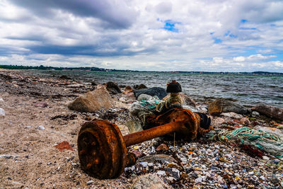 Rusty metal on beach against sky