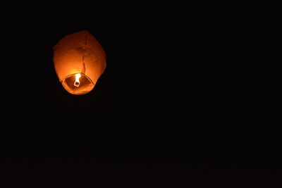 Low angle view of illuminated lantern against black background