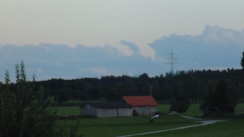 Houses and trees on field against sky