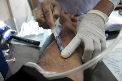Midsection of doctor injecting patient at hospital