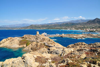 Scenic view of sea and mountains against blue sky