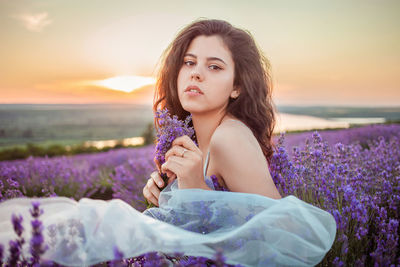 A beautiful young girl against the sunset and a beautiful sky in a lavender field. 