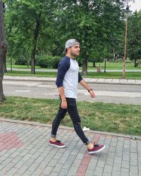 Side view of fashionable man walking on footpath at park