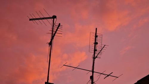 Low angle view of silhouette communications tower against sky during sunset