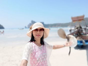 Portrait of woman with hat standing on beach