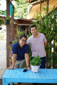 Portrait of men standing by table against plants