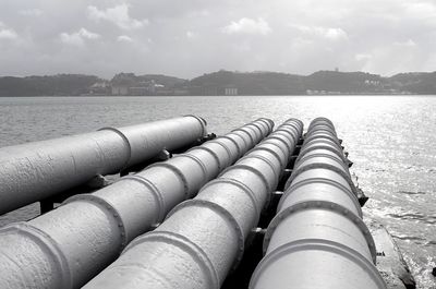 Close-up of pipes in water against sky