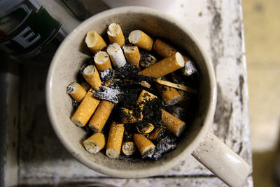 Directly above shot of cigarette butts in cup on table