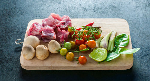 Tomatoes and meat on cutting board over table