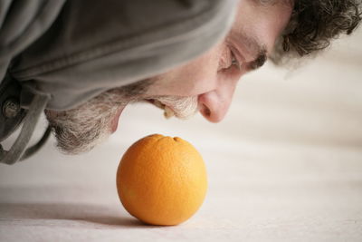 Close-up of man eating orange fruit