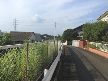 Walkway amidst houses and buildings against sky