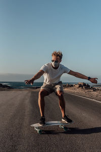 Full length of man on electric skateboard  against clear sky