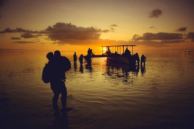 Silhouette people on beach against sky during sunset