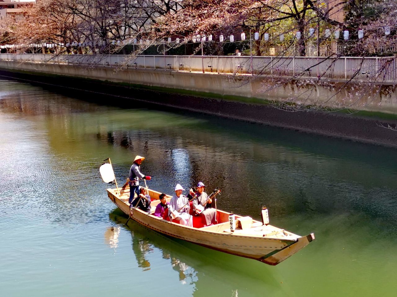 water, nautical vessel, transportation, river, mode of transportation, group of people, men, boat, nature, vehicle, tree, adult, boating, plant, women, travel, day, lifestyles, reflection, canoe, watercraft, leisure activity, waterway, waterfront, outdoors, sitting, group, togetherness, travel destinations, person, holiday, tourism