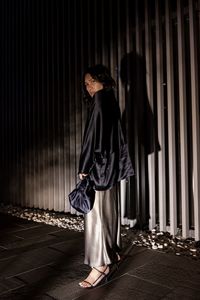 Side view of woman standing against wall