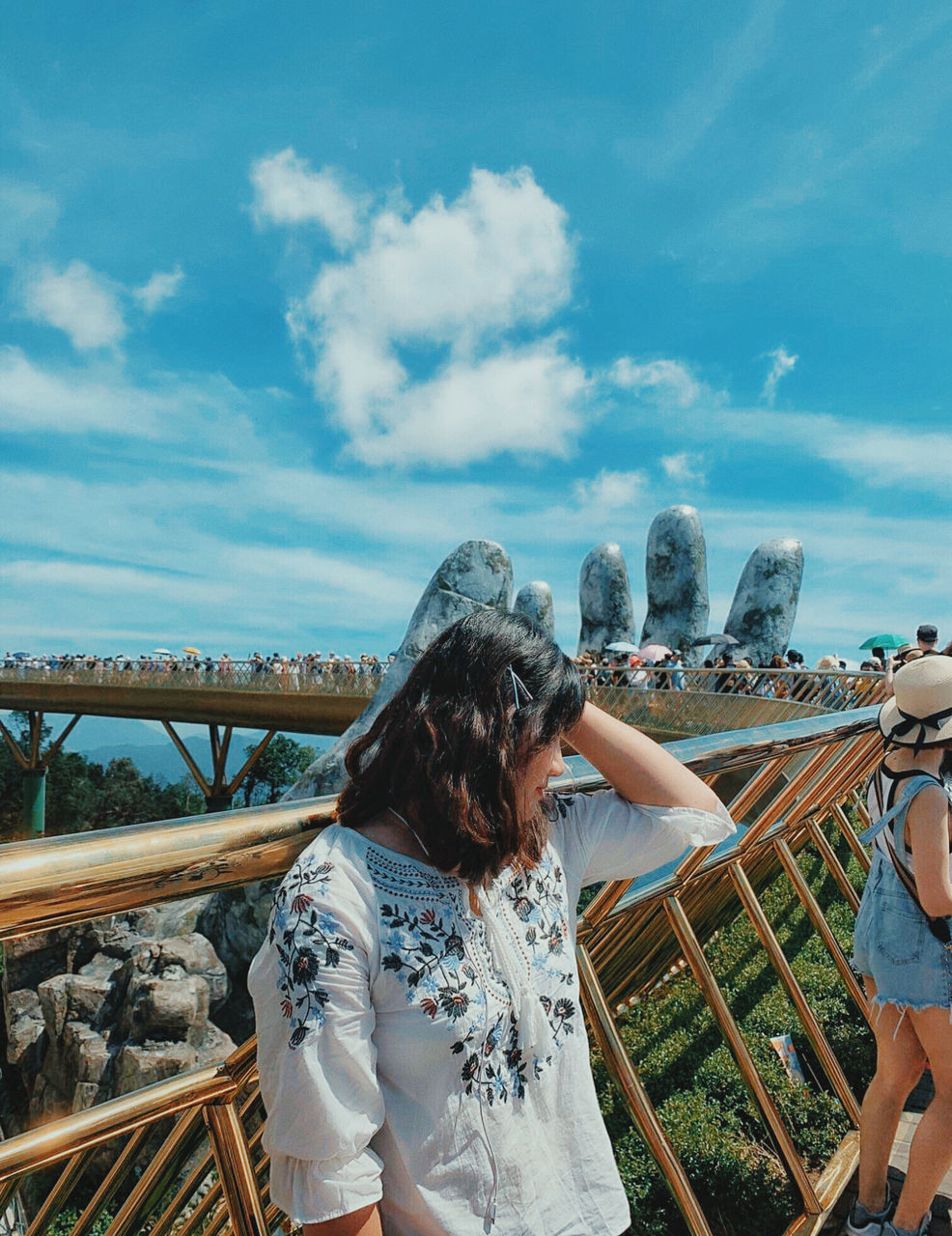 REAR VIEW OF WOMAN STANDING AGAINST RAILING