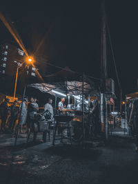 Group of people at illuminated cafe at night