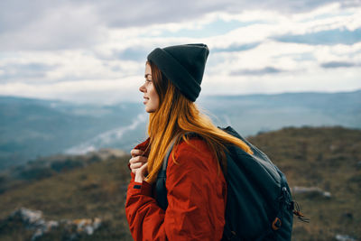 Side view of young woman looking away against mountain