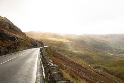 Road leading towards mountains against sky