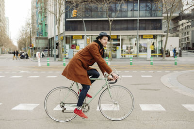 Mid adult male hipster riding bicycle in city