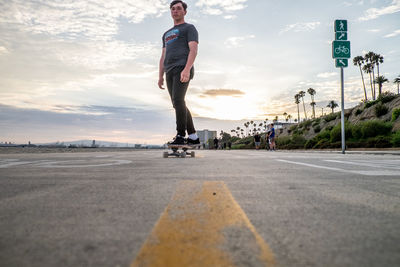 Man skateboarding on road in city against sky