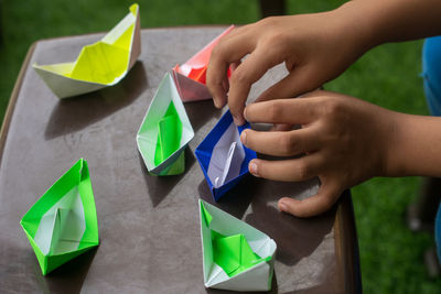 High angle view of hand holding paper painting on table