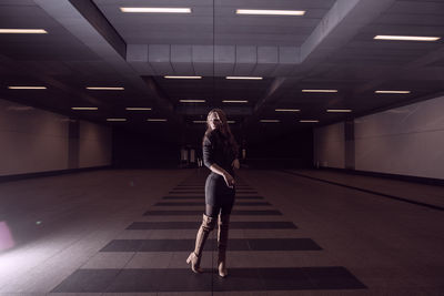 Full length of woman standing in illuminated subway