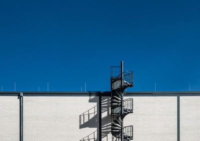 Low angle view of staircase by building against clear sky