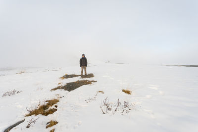 Rear view of man on shore against sky during winter