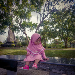 Rear view of woman with pink umbrella against trees