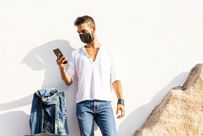 Young man wearing sunglasses standing against wall