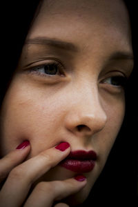 Close-up portrait of beautiful young woman over black background