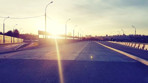 Road by city against sky during sunset