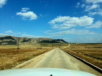 Road amidst landscape against sky seen through car windshield