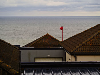 Red house by sea against sky