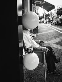 Rear view of man sitting on seat in city