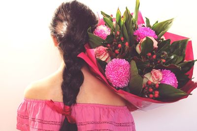 Midsection of woman standing by pink flowering plant against white background