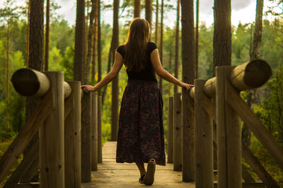 Rear view of woman standing against trees