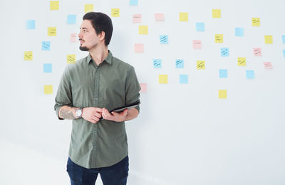 Man holding digital tablet against wall