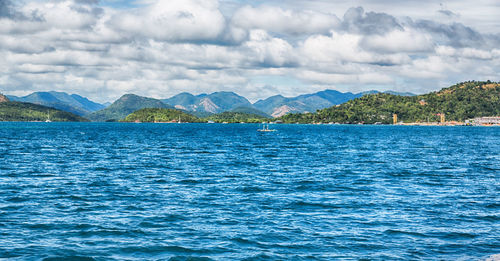 Scenic view of sea and mountains against sky