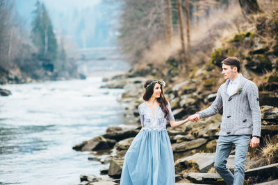 Couple holding umbrella on water with reflection in background