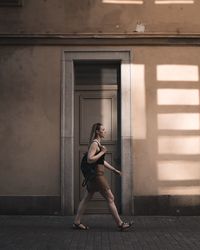 Woman walking on footpath by building