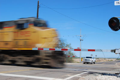 Train passing by railroad crossing against clear blue sky